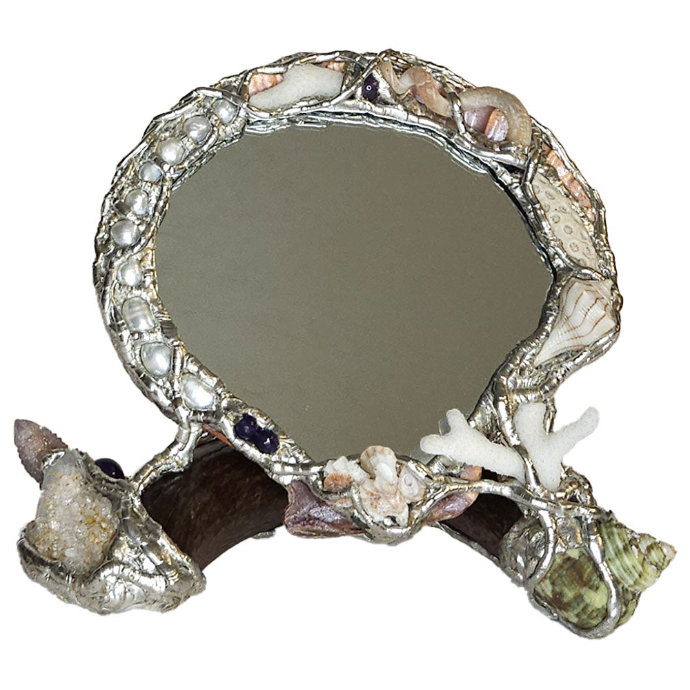 Found along the shores of Sanibel Island, FL is a lion paw table mirror resting on an elk antler. Front view.
