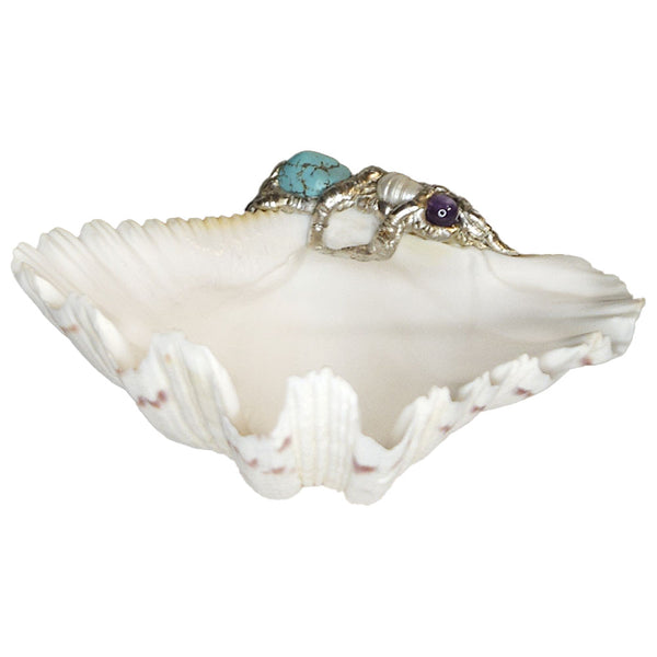A small bear claw clam shell bowl has been adorned with a turquoise nugget, amethyst ball and a potato white pearl. Comes with a small leucite stand.