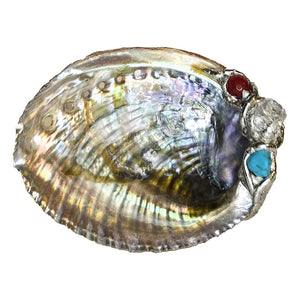 A crystal-clear quartz point is set on this small abalone shell jewelry bowl with a ruby crystal ball and a small turquoise ball.