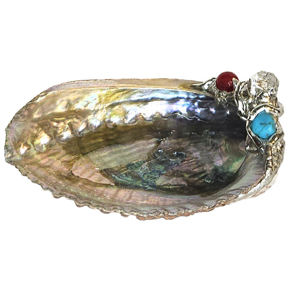 A crystal-clear quartz point is set on this small abalone shell jewelry bowl with a ruby crystal ball and a small turquoise ball.
