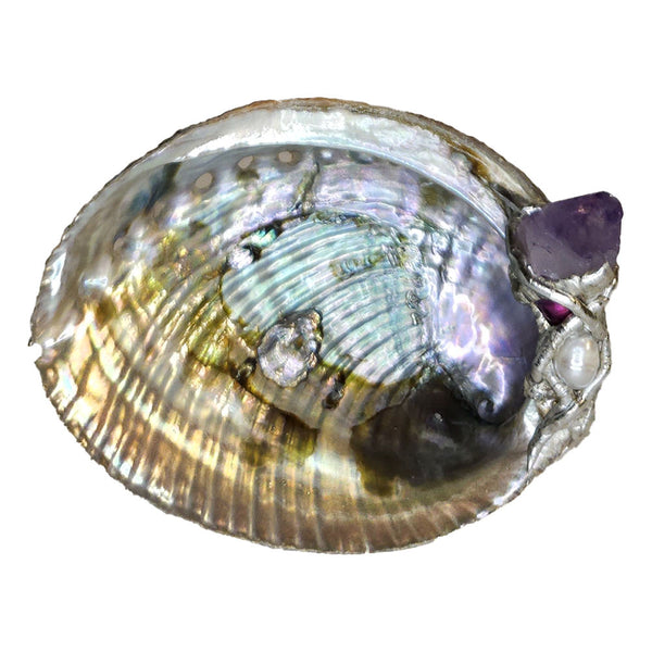 This small abalone shell is graced with a lovely amethyst point, small purple pearl and a small white pearl. Comes with a leucite stand.