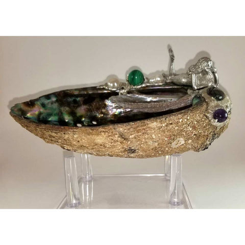 Water nymph resting on a blue-green abalone shell. A small pink abalone is within the larger shell. A malachite ball, amethyst bead and two white pearls are joined with a blue hued labradorite.  Front view.